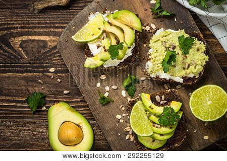 Sandwiches With Avocado And Cream Cheese With Grain Bread. Dark Wooden Background, Top View.