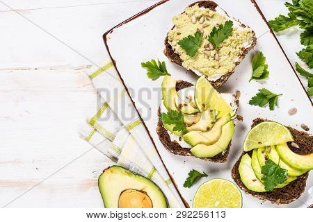 Sandwiches With Avocado And Cream Cheese With Grain Bread. White Wooden Background, Top View.