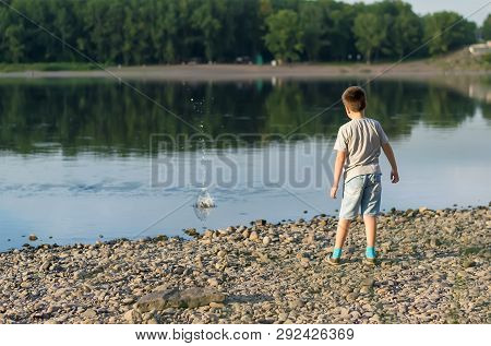 A Child, A Teenager, On A Stony Shore Throws Stones Into The River, Lake