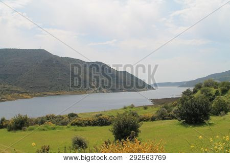Panoramic View Of Kouris Water Reservoir In Cyprus, A Green Valley And The Mountains Around On A Clo