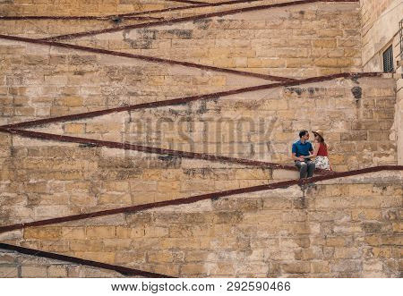 Man With Woman Sitting On The City Walls, Old City Of The Three Cities, Malta