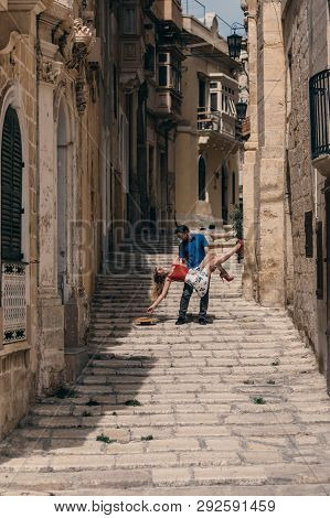 Man Holding Woman On Hands On The Street, Old City Of The Three Cities, Malta