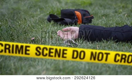 Crime Scene Do Not Cross Tape And A Victim In The Background. Selective Focus.