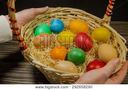 Close Up View Of Colored Eggs In Wicker Basket In The Hands Of A Perso . Easter Background. Decorati