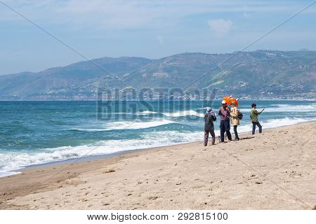 Malibu, California - March 26, 2019: Adult Tourists Take Selfies And Photos, Posing With Umbrella Pr