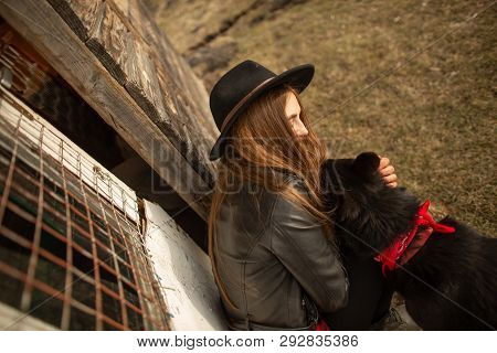 Happy Young Woman Plaing With Her Black Dog Brovko Vivchar In Fron Of Old Wooden House.