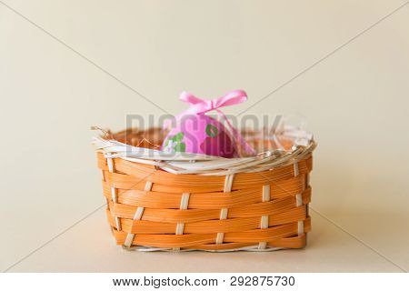 Easter Pink Egg In Nature Wicker Basket On The Bastel Background. Easter Concept.