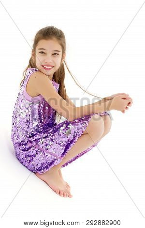 A Cute Little Girl Leaned Against A White Wall. Cyclorama In Studio. Isolated On A White Background.