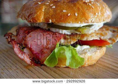 Closeup Of Grilled Burger With Salad And Backon On Cutting Board