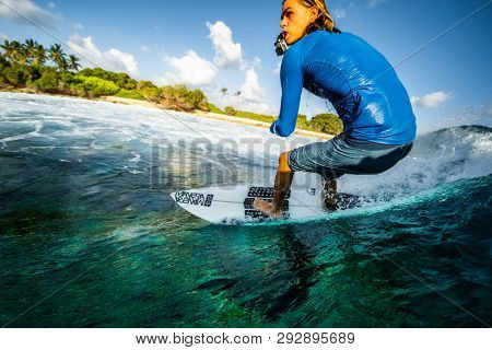 MALDIVES / HURAA - 22 MARCH 2019: Young man rides the ocean wave with camera in his mouth at famous Honkys surf spot in the Maldives