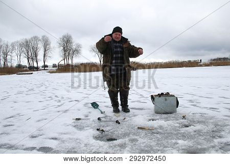 Man Ice Fishing On A Frozen Lake. Winter Holidays And People Concept. Winter Fishing, Ice Fishing. B