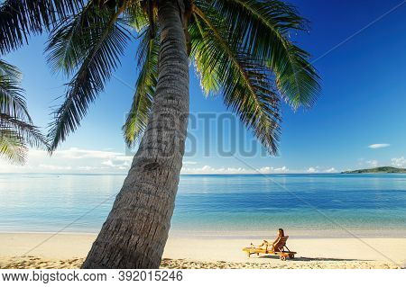 Young Woman Sitting In A Sun Chair On The Beach, Nacula Island, Yasawas, Fiji