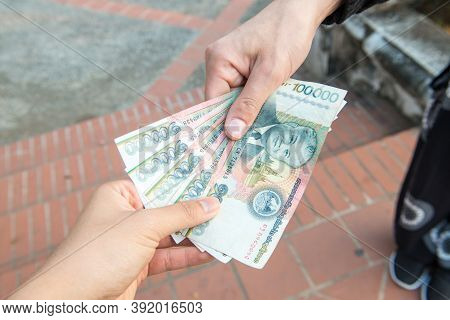 Cropped Shot View Of Someone Giving Or Payment Banknotes Of Laos Kip Money To Other Person. Kip Is T