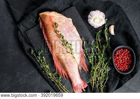Raw Red Sea Perch On A Stone Board With Thyme. Black Background. Top View