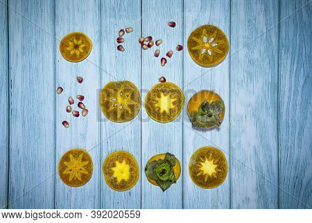 Set Of Yellow Persimmon Fruits And Pomegranate Seeds On Turquoise Wooden Background, Selective Focus