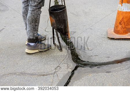 Man Sealing Asphalt Driveway With Filled Cracks Sealcoating Selective Focus