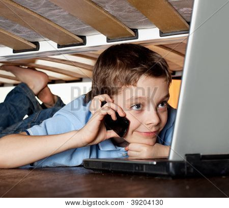Enfant jeu portable sous le lit. Ordinateur Addiction