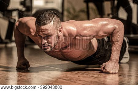Man Doing Push-ups. Muscular Man Doing Push-ups On One Hand Against Gym Background. Slim Man Doing S