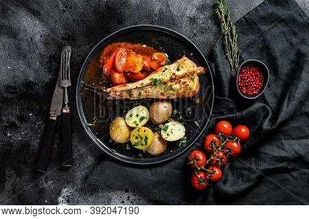 Baked In Tomatoes Monkfish With Potatoes And Vegetables. Black Background. Top View