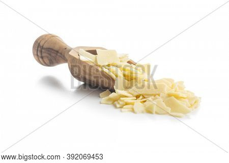 Grated white chocolate in wooden scoop. Chocolate flakes isolated on a white background.