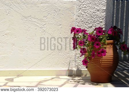 Typical Greek Courtyard With Colorful Flowers In A Traditional Ceramic Vase. Background Of A Plain W