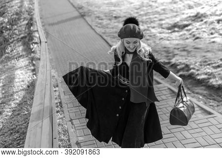 A Woman Walks Up The Stairs And In Burgundy. Black And White Palette And Biret, Looking At The Camer
