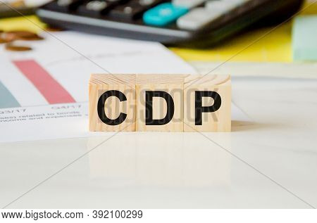 The Word Is Written On Wooden Cubes, In The Background Is A Calculator On A Financial Chart. The Wor