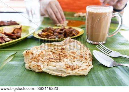 Roti Canai Or Paratha Served On Banana Leaf, With Mutton Curry And Fried Chicken, And Popular Teh Ta