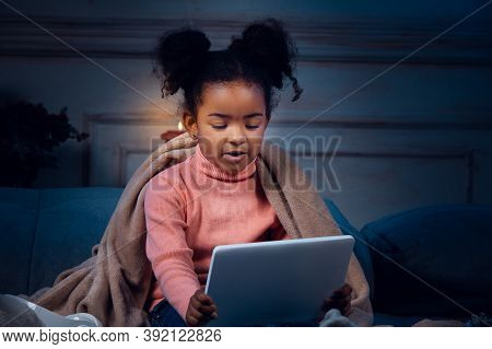 Happy African-american Little Girl During Video Call With Laptop And Home Devices, Looks Delighted A