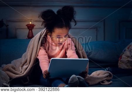Happy African-american Little Girl During Video Call With Laptop And Home Devices, Looks Delighted A