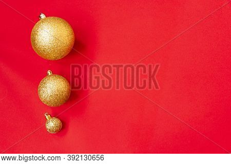 Three Golden Christmas Balls Of Different Sizes Are Displayed In A Row As A Border On A Red Backgrou