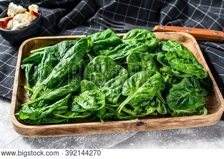 Fresh Spinach Salad In A Wooden Bowl With Goat Cheese. Gray Background. Top View