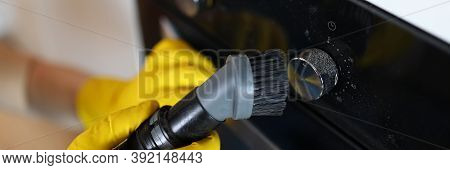 Close-up Of Male Hands In Yellow Gloves Vacuuming Cookstove Handle With Special Vacuum Cleaner After