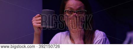 Portrait Of Tired Young Woman Yawning Sitting In Room With Cup Of Coffee And Accounting Money From P