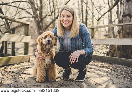 Happy Labradoodle Dog And Woman Outside At The Park