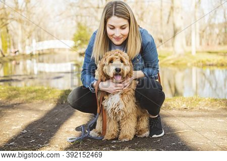 Happy Labradoodle Dog And Woman Outside At The Park