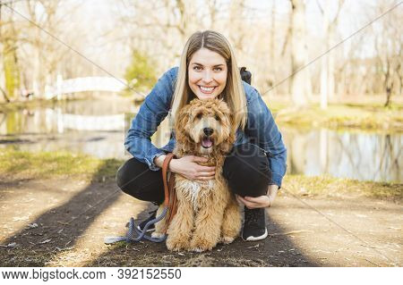 Happy Labradoodle Dog And Woman Outside At The Park
