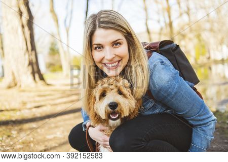 Happy Labradoodle Dog And Woman Outside At The Park