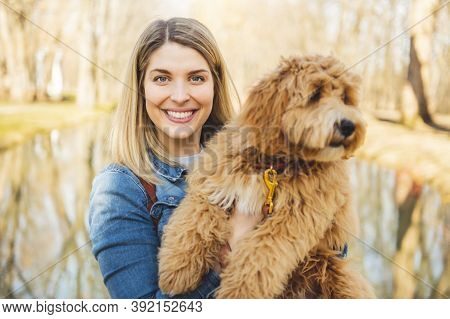 Happy Labradoodle Dog And Woman Outside At The Park