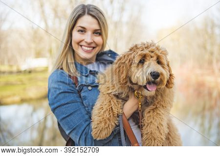 Happy Labradoodle Dog And Woman Outside At The Park