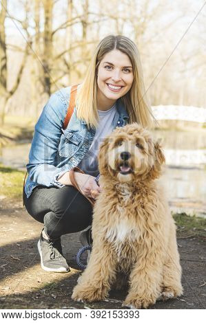Happy Labradoodle Dog And Woman Outside At The Park
