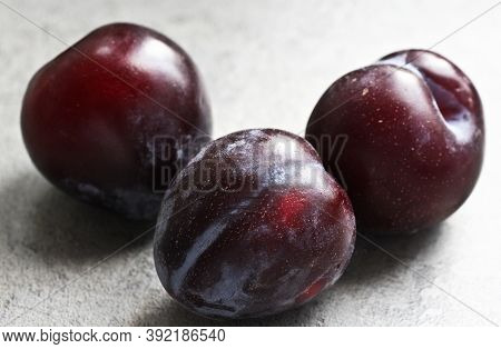 Three Ripe Plums On A Background Of A Gray Table Top In The Kitchen. A Portion Of Fruits.