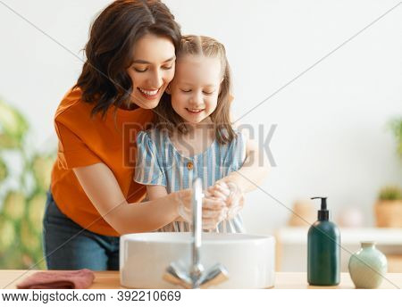 A cute little girl and her mother are washing their hands. Protection against infections and viruses.     