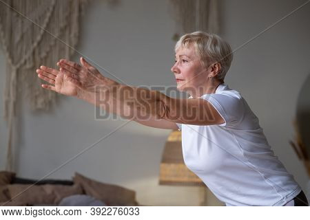 Senior Caucasian Woman Practicing Advanced Yoga Chair Pose Or Utkatasana