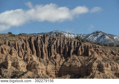 Landscape Of Grassy Plain, Sagebrush, And Colorful Cliffs Under A Vast Blue Sky In The High Desert L