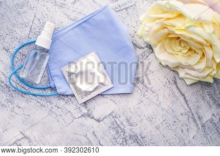 Protective Medical Mask, Rose, Condom And Sanitizer On A White Textured Background. The Concept Of L