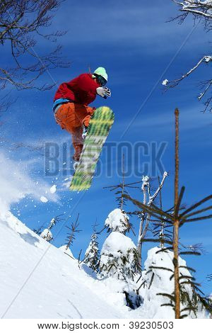 Snowboarder jumping against blue sky