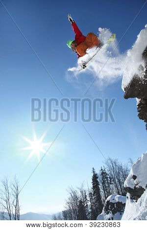 Snowboarder jumping against blue sky