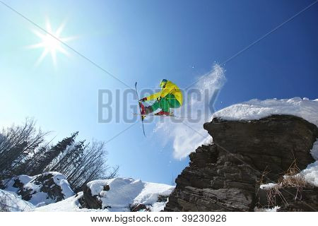 Skier jumping against blue sky from the rock
