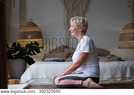 Woman Doing Yoga Exercise On Mat In Virasana Or Hero Pose With Reversed Prayer At Home.